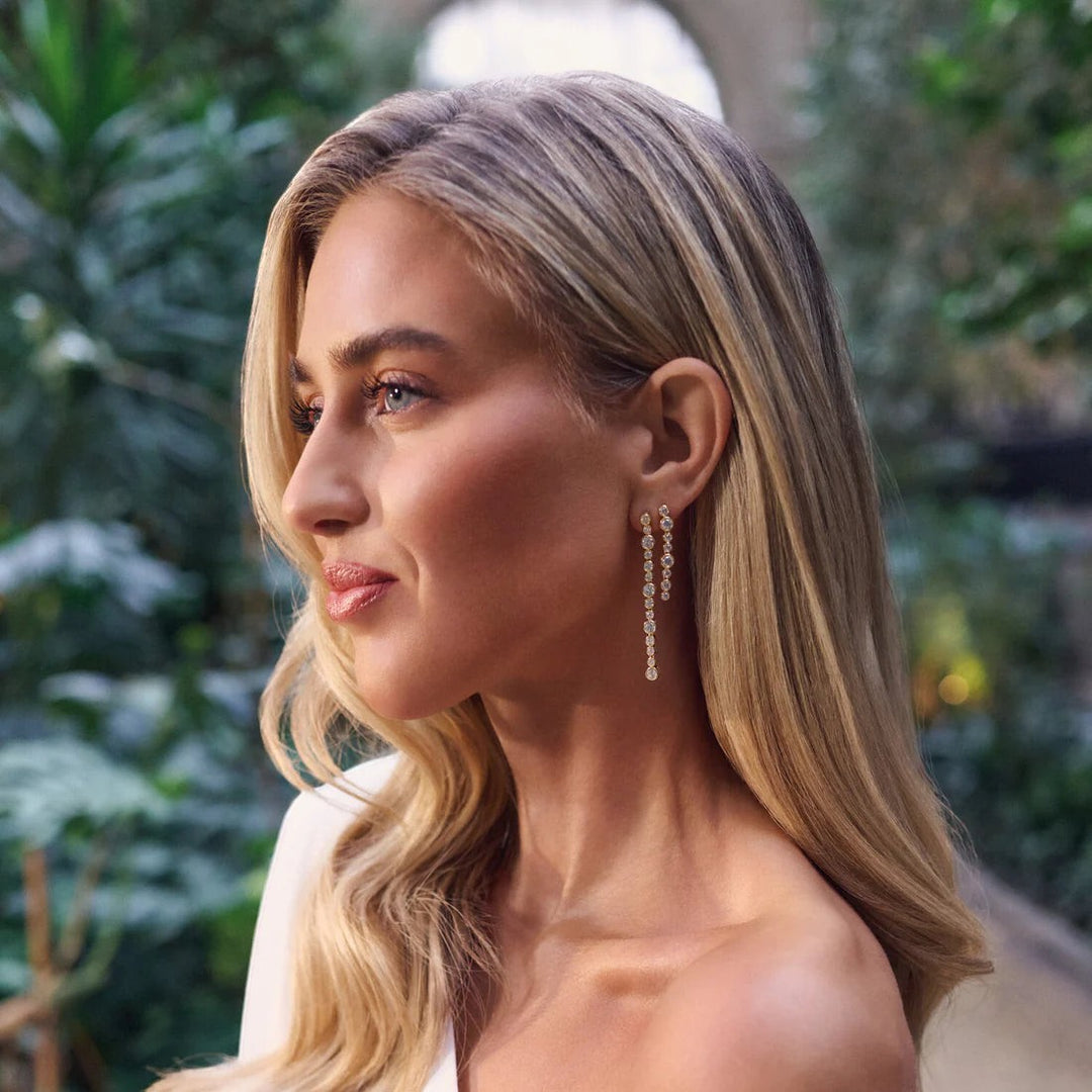 Model wearing Niche Jewellery Sif Jakobs Sardinien gold-plated drop earrings with sparkling white zirconia stones.