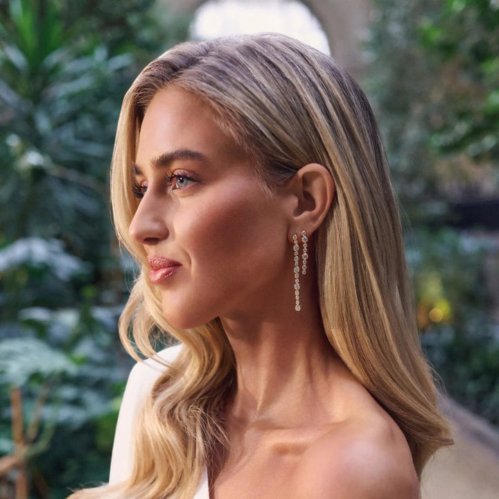 Model wearing Niche Jewellery Sif Jakobs Sardinien gold-plated drop earrings with sparkling white zirconia stones.