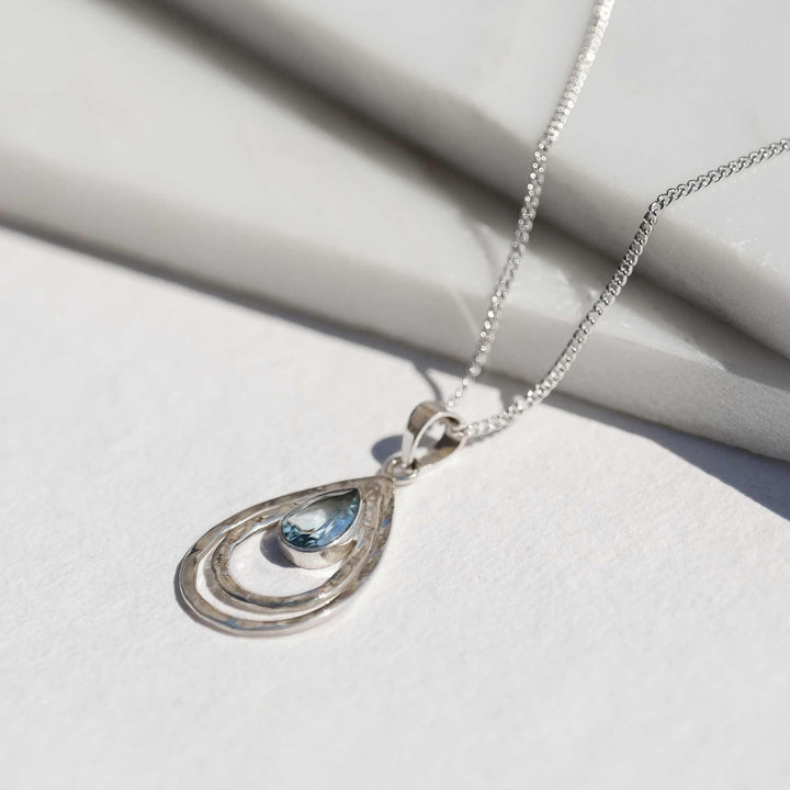 Niche Jewellery Charlotte's Web sterling silver infinity pendant necklace featuring a teardrop blue topaz stone on a delicate chain.
