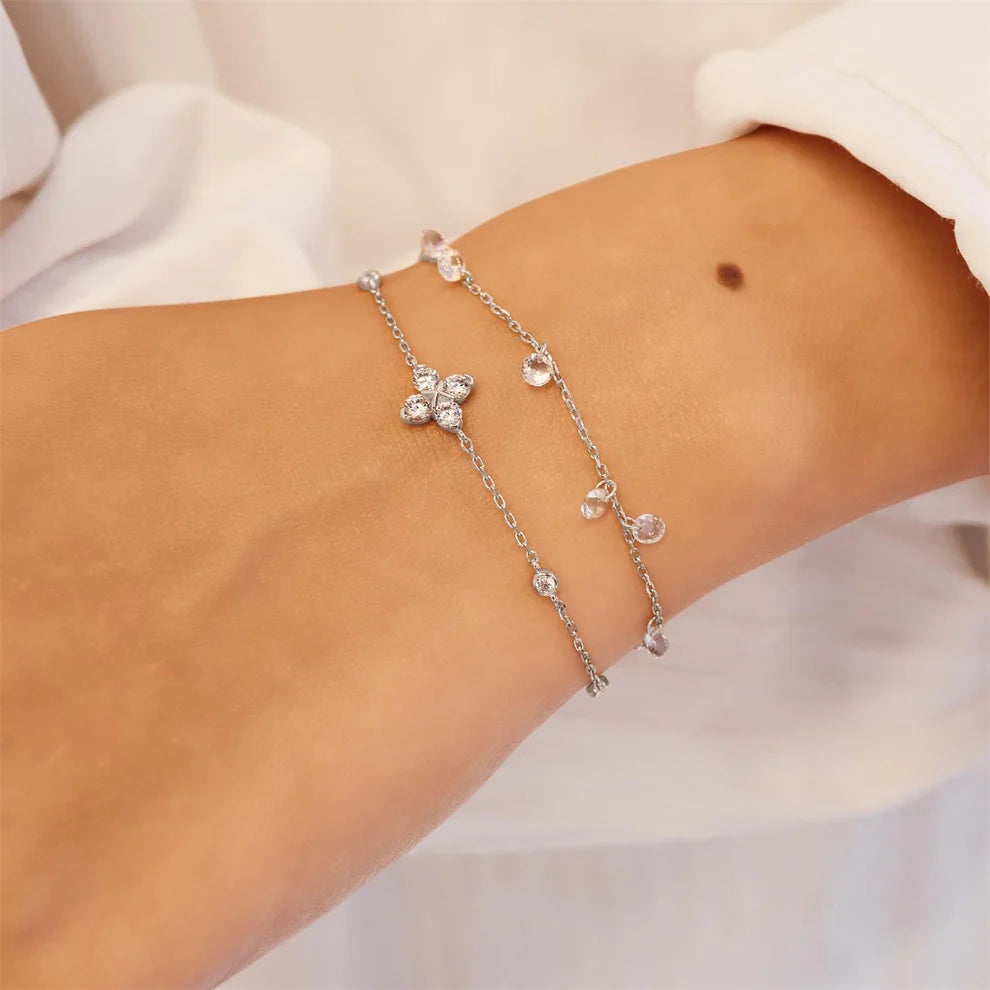Niche Jewellery Ania Haie silver bracelet featuring a sparkling four-leaf clover charm and delicate crystal stations.
