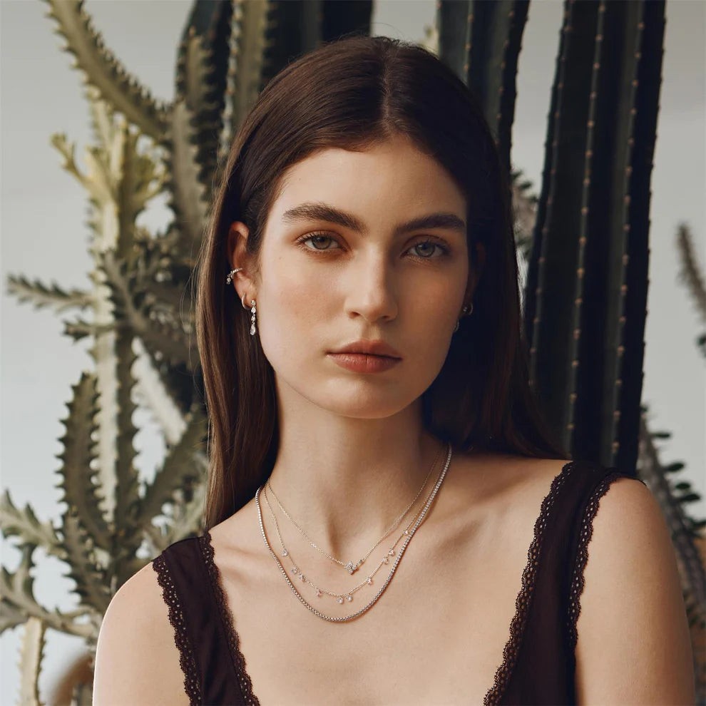 Model wearing Niche Jewellery Ania Haie silver clover necklace with cubic zirconia against a cactus background