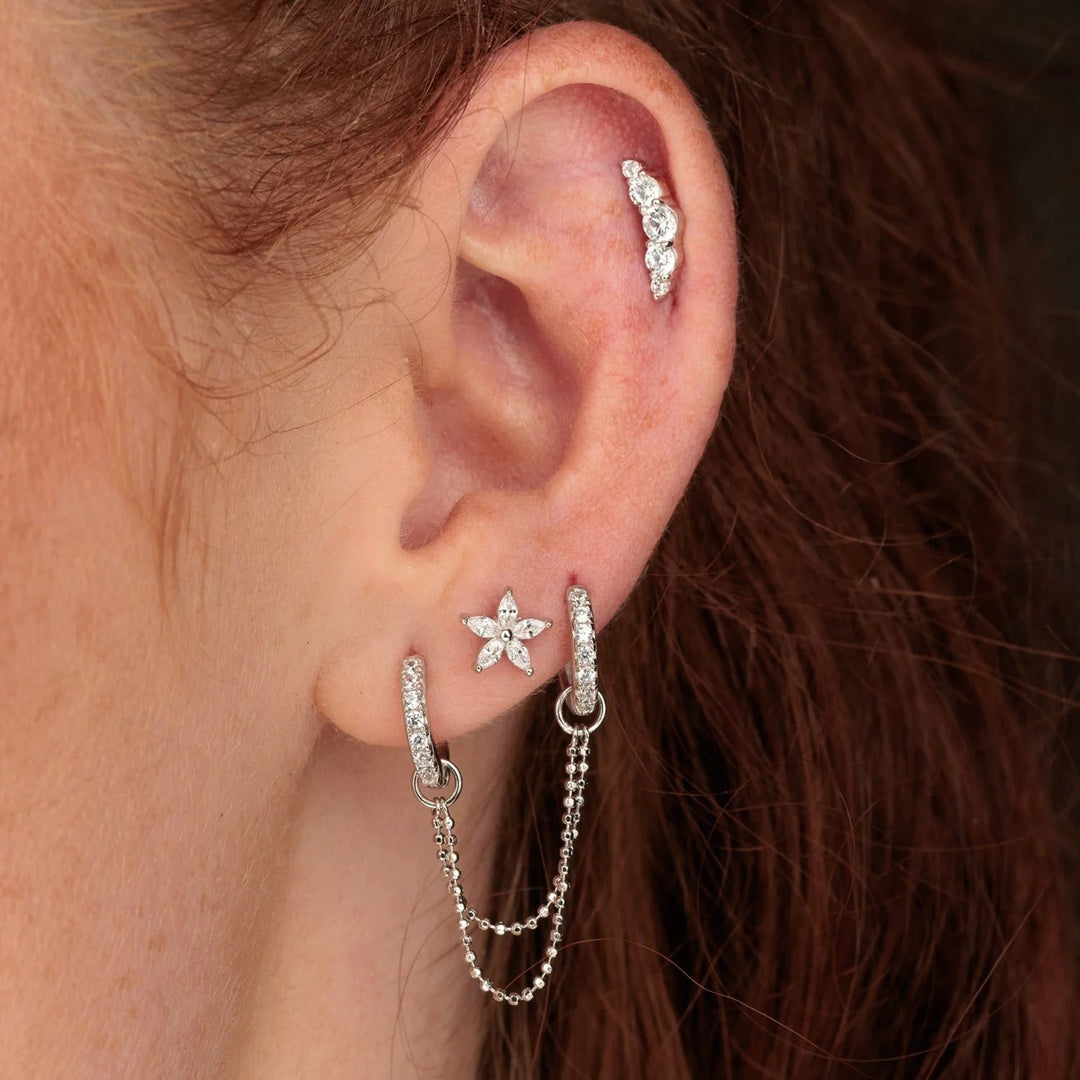Niche Jewellery Scream Pretty sterling silver teeny flower stud earring with sparkling stones worn in a curated ear stack