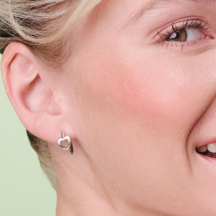 Niche Jewellery Olivia Burton Kindred silver-tone hoop earrings with an open heart design worn on a model