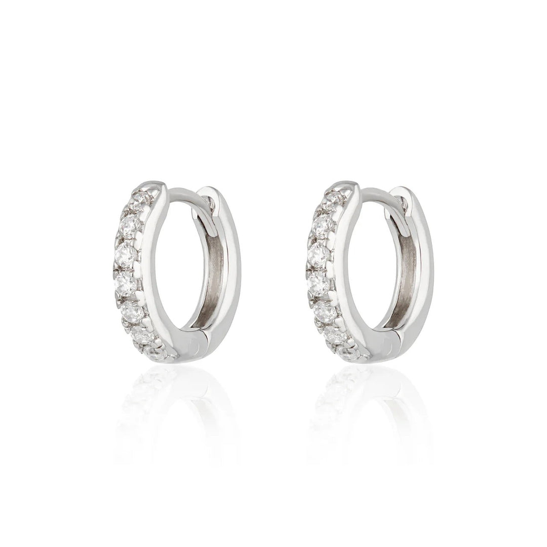 Niche Jewellery Scream Pretty silver huggie hoop earrings featuring a row of sparkling clear stones.