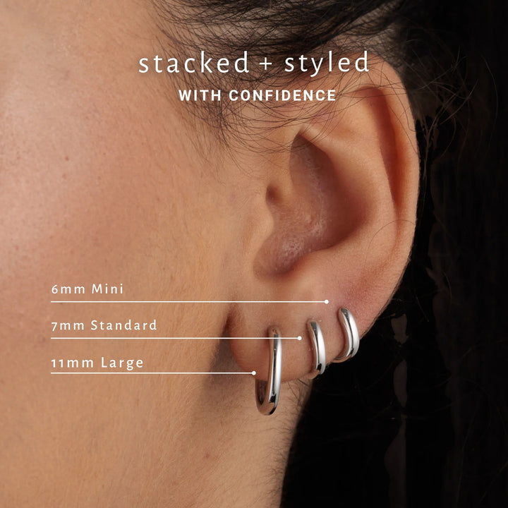Niche Jewellery Scream Pretty silver mini huggie hoop earrings worn in a stacked ear piercing style.