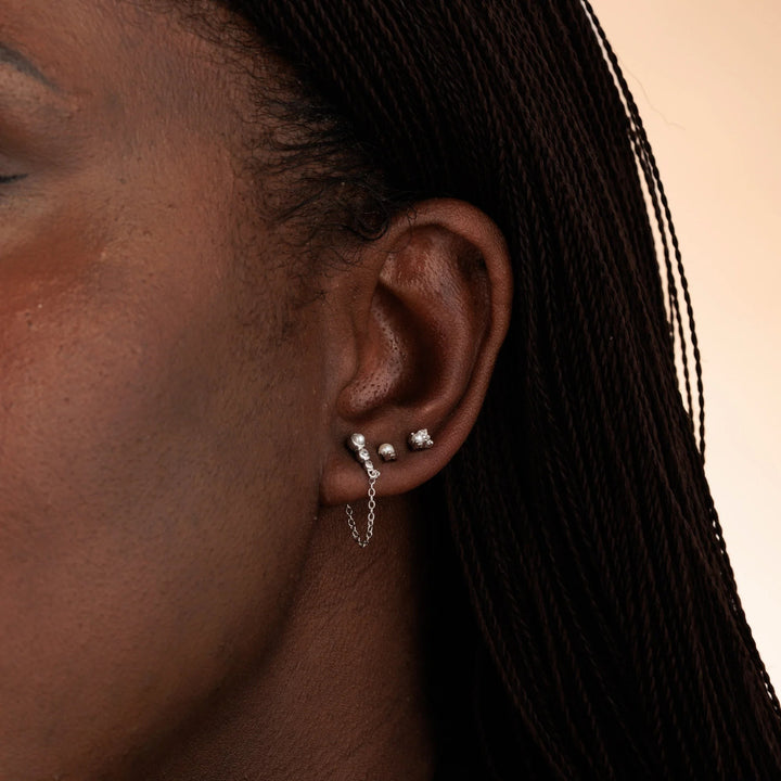 Niche Jewellery Scream Pretty sterling silver pearl stud earring worn on a model ear with other delicate piercings