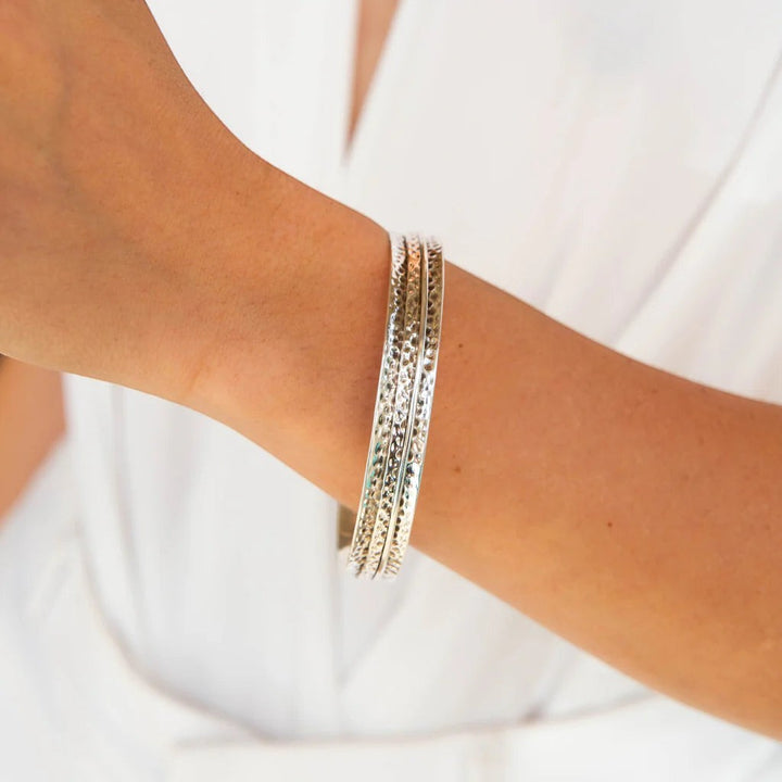 Niche Jewellery Charlotte's Web sterling silver Karma Abundance spinning bangle worn on a wrist with a textured hammered finish.