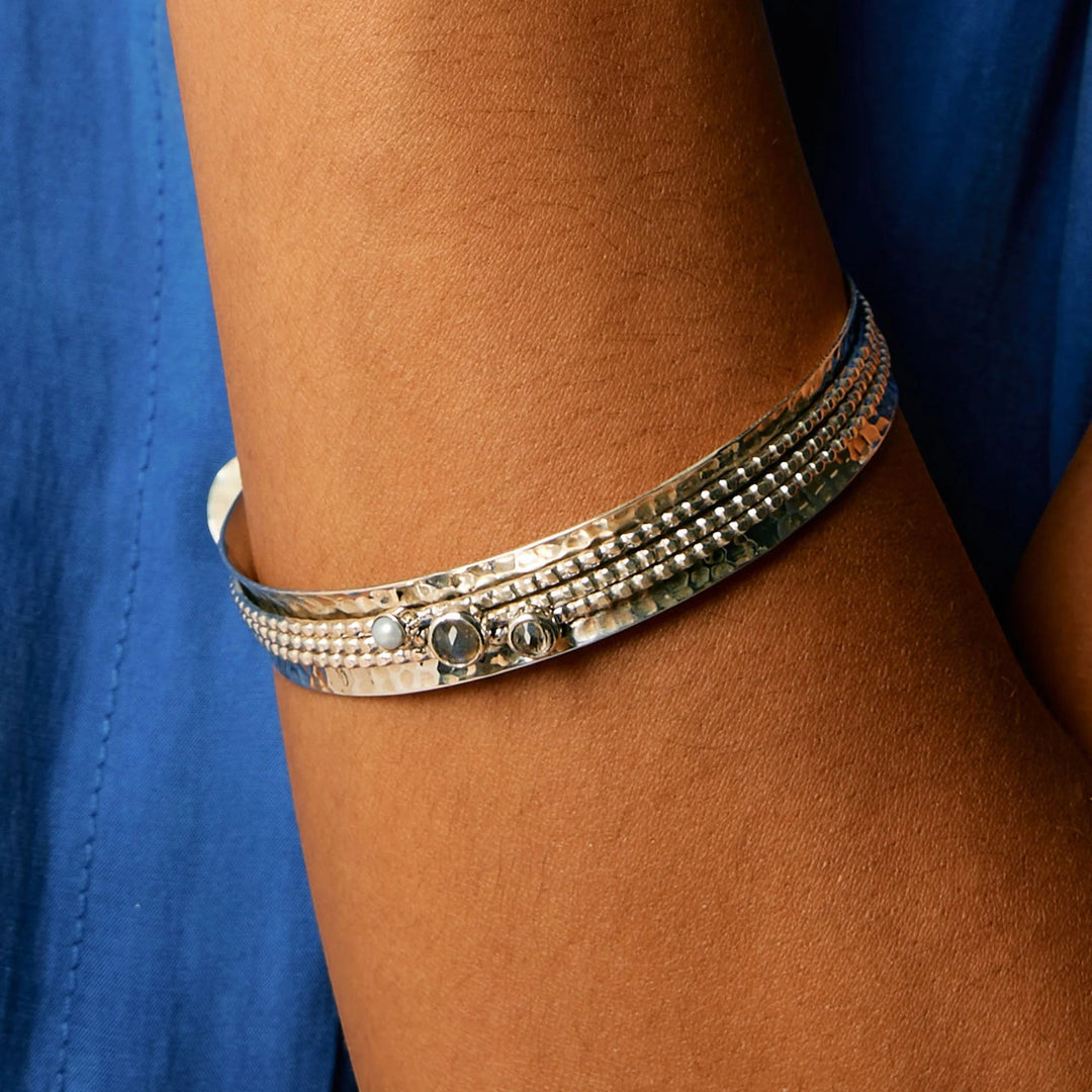 Niche Jewellery Charlotte's Web sterling silver spinning bangle featuring labradorite, white topaz, and pearl on a textured band.