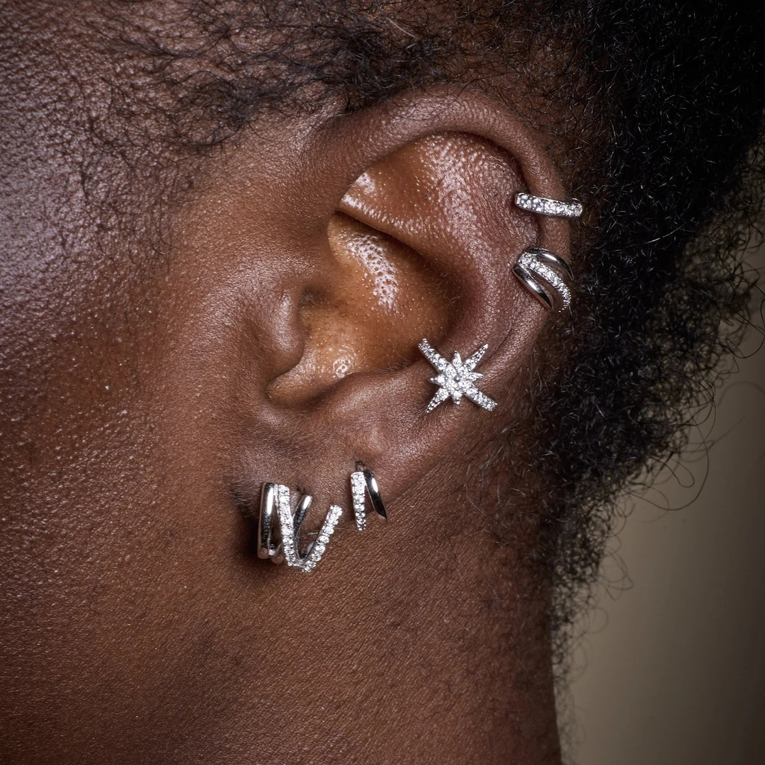 Niche Jewellery Scream Pretty silver split mini huggie earrings worn on a model ear with multiple piercings