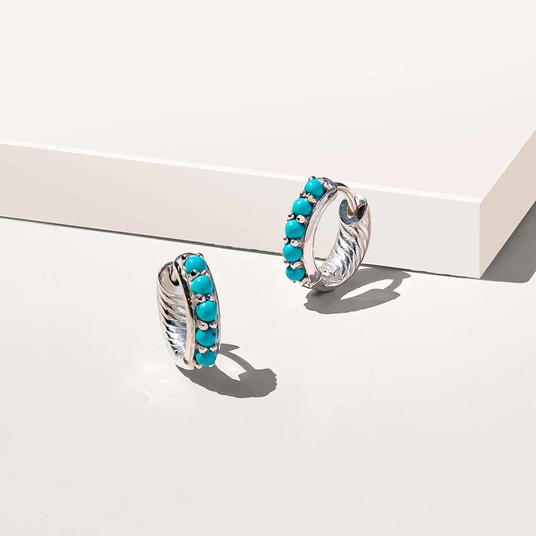 Niche Jewellery Charlotte's Web Kali huggie hoops in recycled sterling silver with turquoise beads on a white surface.