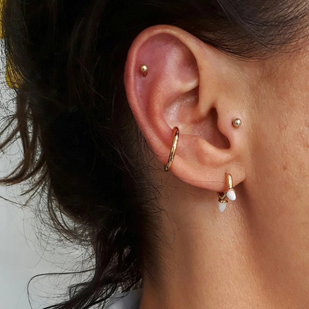 Niche Jewellery Scream Pretty slim gold ear cuff worn on a model's ear as part of a curated stack.