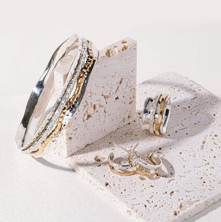 Niche Jewellery Charlotte's Web spinning bangle, ring, and hoop earrings in recycled sterling silver and brass.