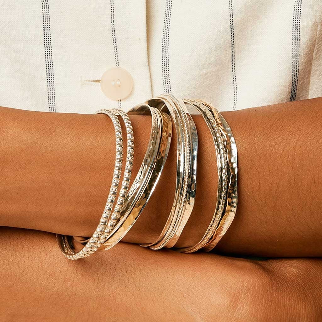 Niche Jewellery Charlotte's Web Aura Magic spinning bangle in recycled sterling silver and brass worn on a wrist.