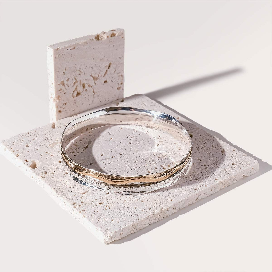 Niche Jewellery Charlotte's Web Aura Magic spinning bangle featuring a warm brass band on textured recycled sterling silver.