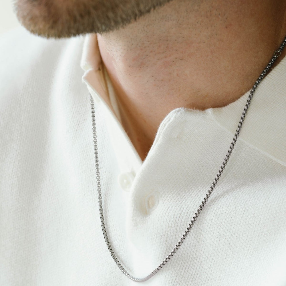 Niche Jewellery thin brushed stainless steel box chain necklace worn by a man in a white polo shirt