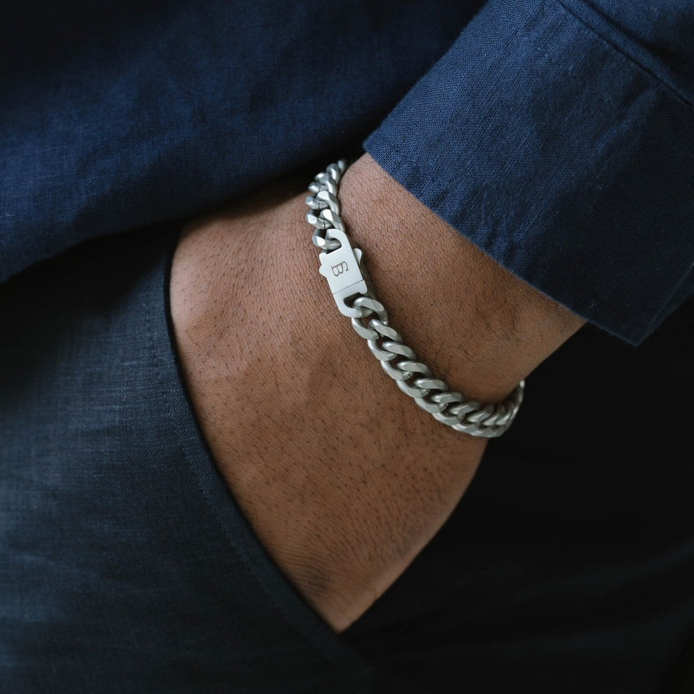 Niche Jewellery stainless steel Cuban link chain bracelet with a brushed clasp worn on a man's wrist
