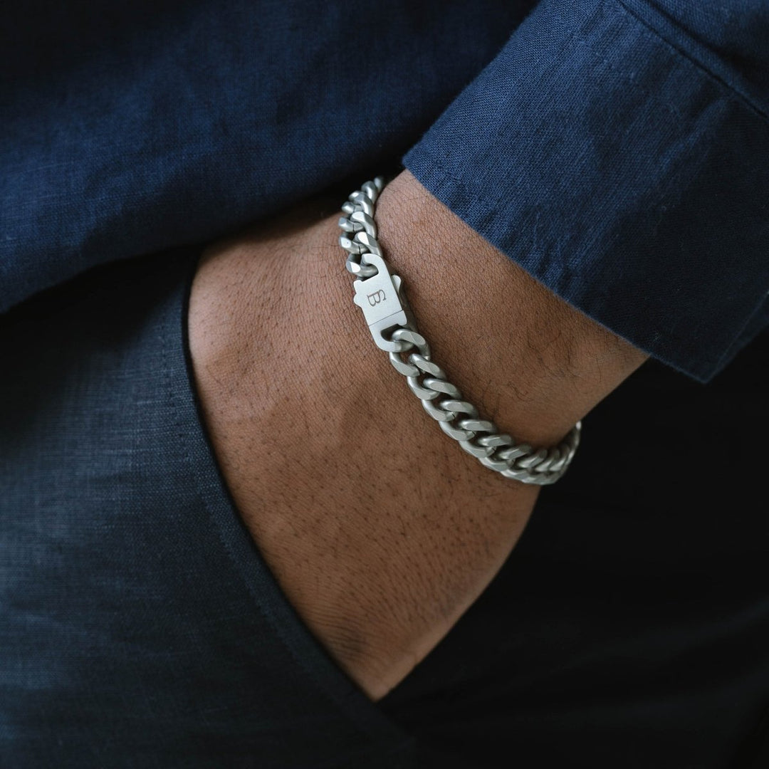 Niche Jewellery stainless steel Cuban link chain bracelet with a brushed clasp worn on a man's wrist