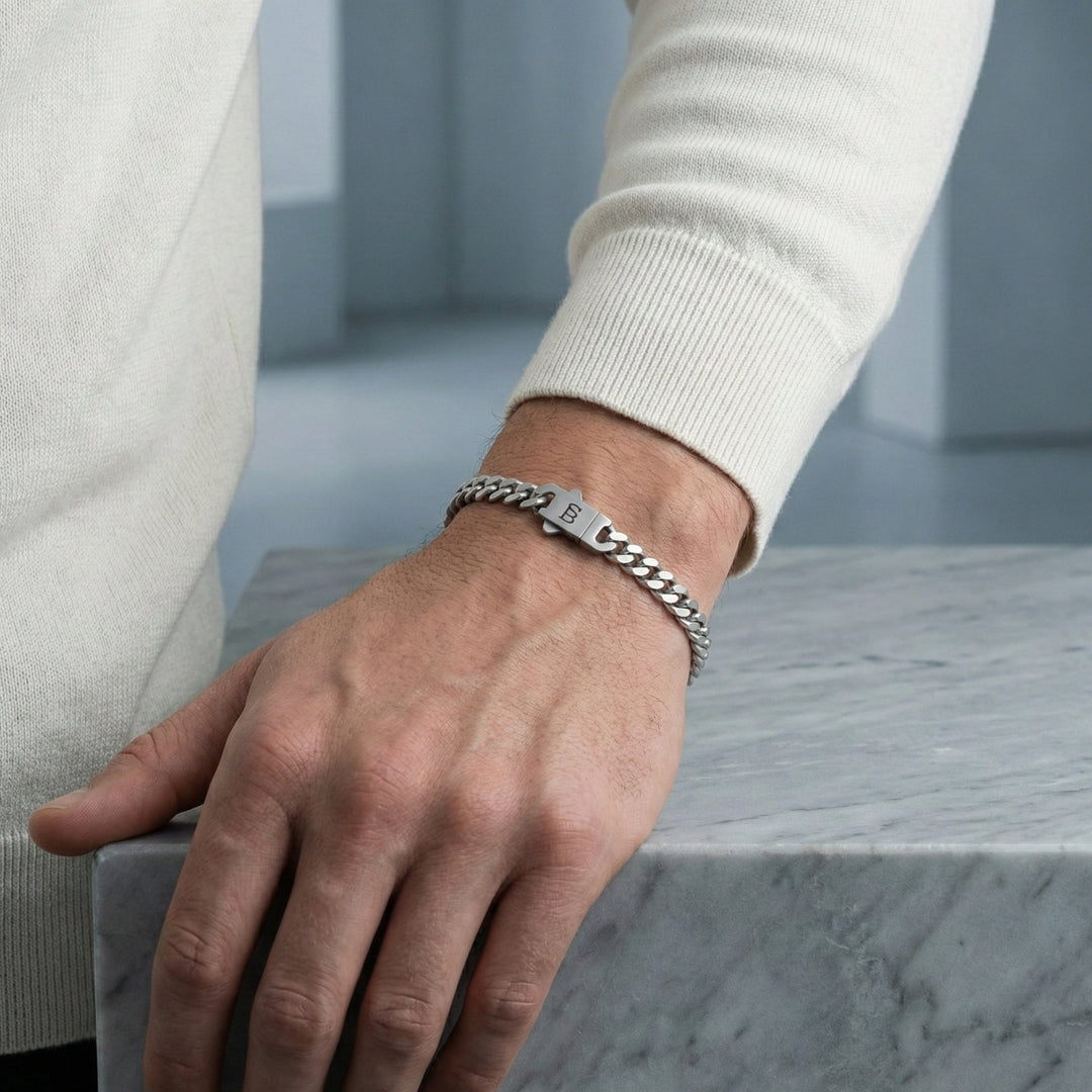 Niche Jewellery Steel & Barnett stainless steel link chain bracelet with a branded clasp worn on a man's wrist.