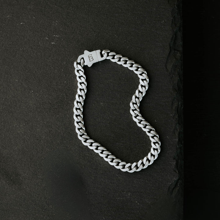 Niche Jewellery Steel & Barnett stainless steel link chain bracelet with a branded clasp on a black slate background.