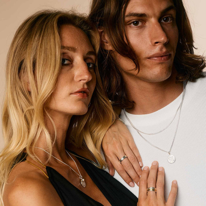Niche Jewellery Charlotte's Web  sterling silver spinning ring worn by a man and woman in a studio portrait.