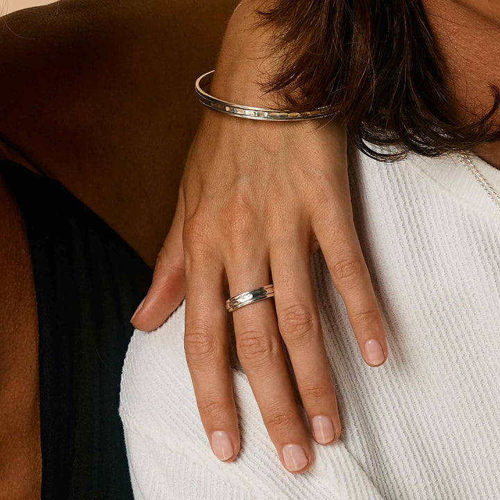 Niche Jewellery Charlotte's Web  sterling silver Karma Abundance spinning ring worn on a hand with a matching silver bangle