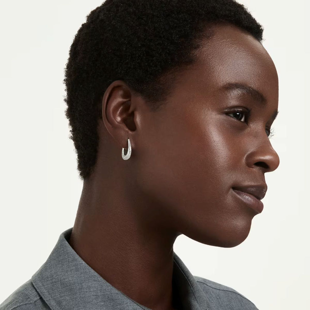 Niche Jewellery Swarovski Classica small hoop earrings with round-cut white crystals worn by a model in profile.