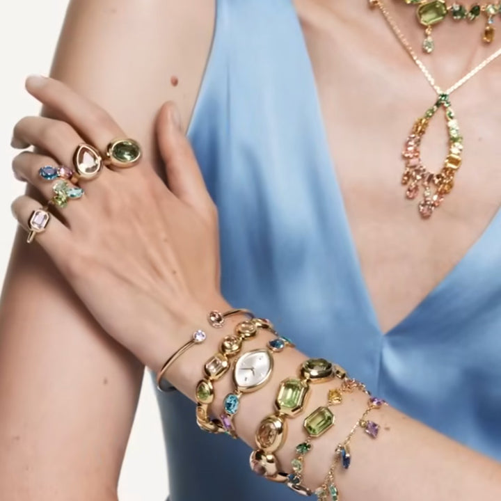 Niche Jewellery Swarovski Gema bangle featuring multicoloured mixed-cut crystals on a gold-tone metal band.