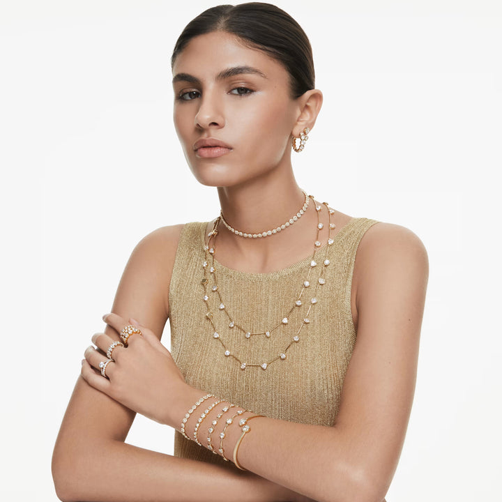 Niche Jewellery Swarovski Imber tennis bracelet in gold tone with round white crystals worn on a model's wrist.
