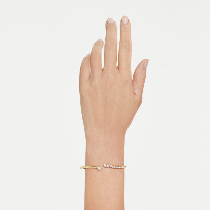 Niche Jewellery Swarovski Mesmera bangle featuring mixed-cut white zirconia stones on an 18k gold-plated open cuff.