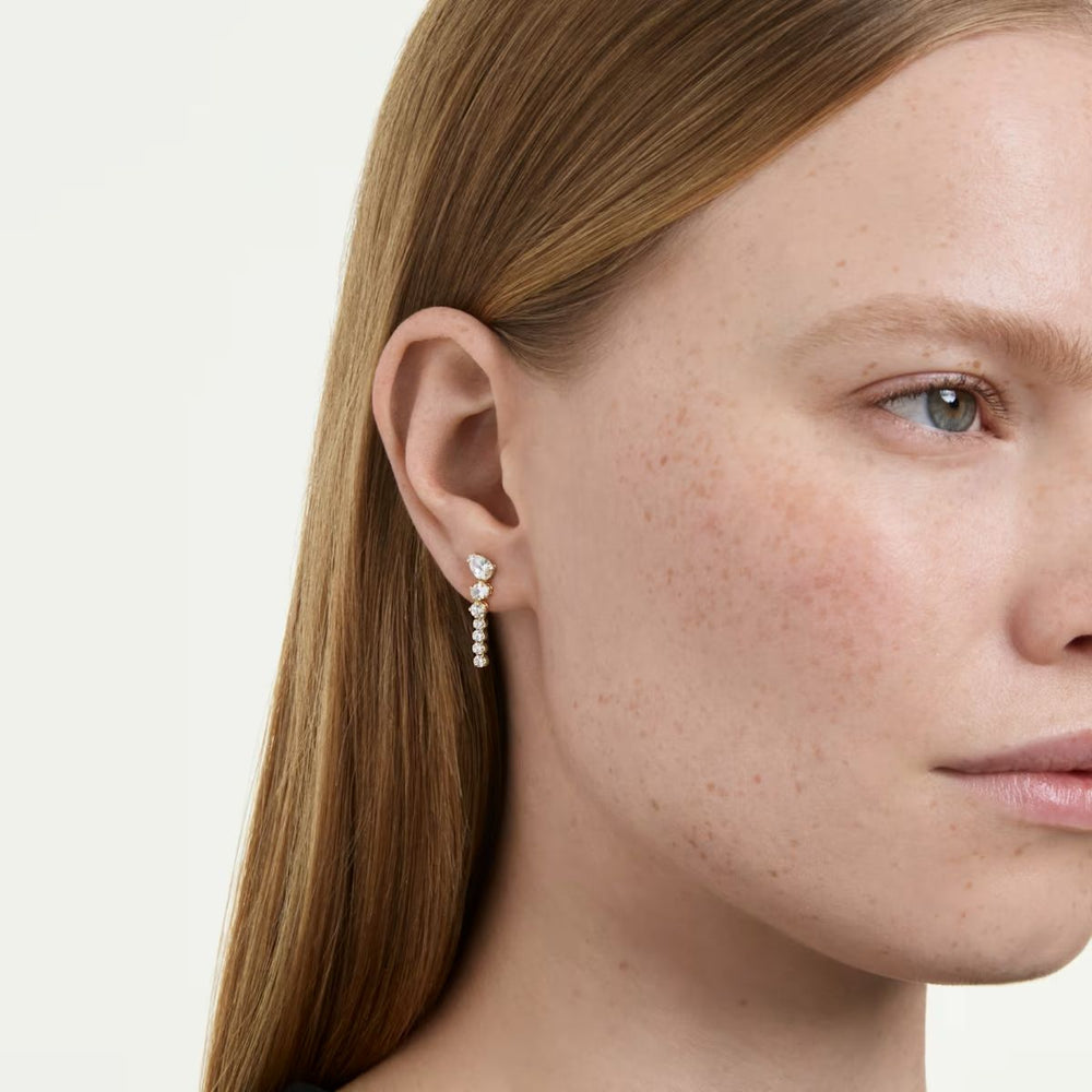 Niche Jewellery Swarovski Mesmera drop earrings featuring mixed cut white zirconia stones in 18k gold finish on model