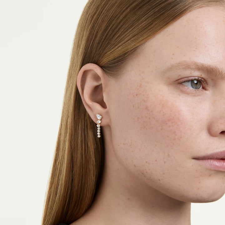 Niche Jewellery Swarovski Mesmera drop earrings featuring mixed cut white zirconia stones in 18k gold finish on model
