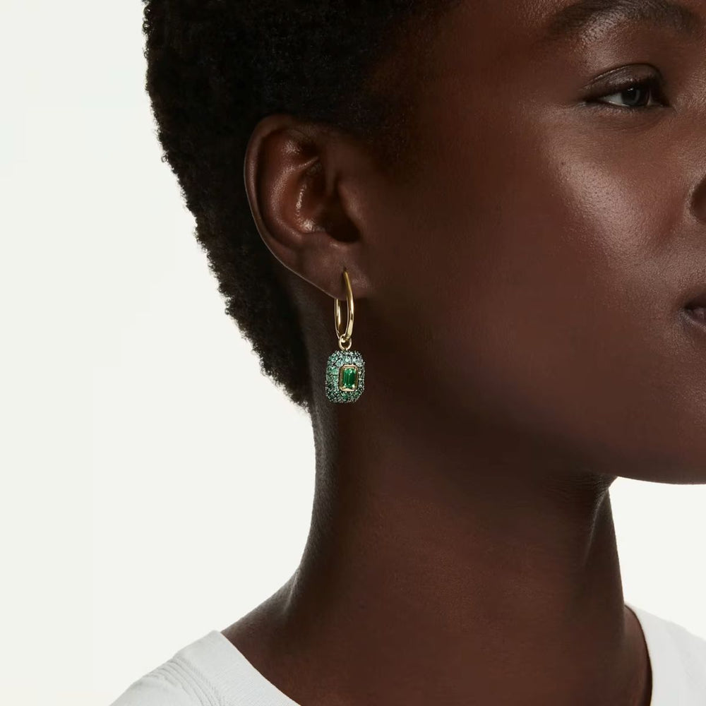 Niche Jewellery Swarovski Sublima drop earrings featuring an octagon-cut green crystal with 18K gold finish on a model