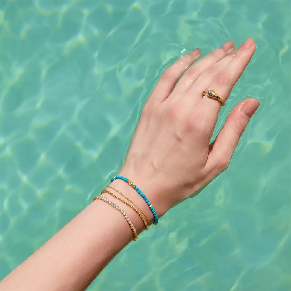 Niche Jewellery Ania Haie textured silver chain bracelet layered with beaded bracelets on a hand in water