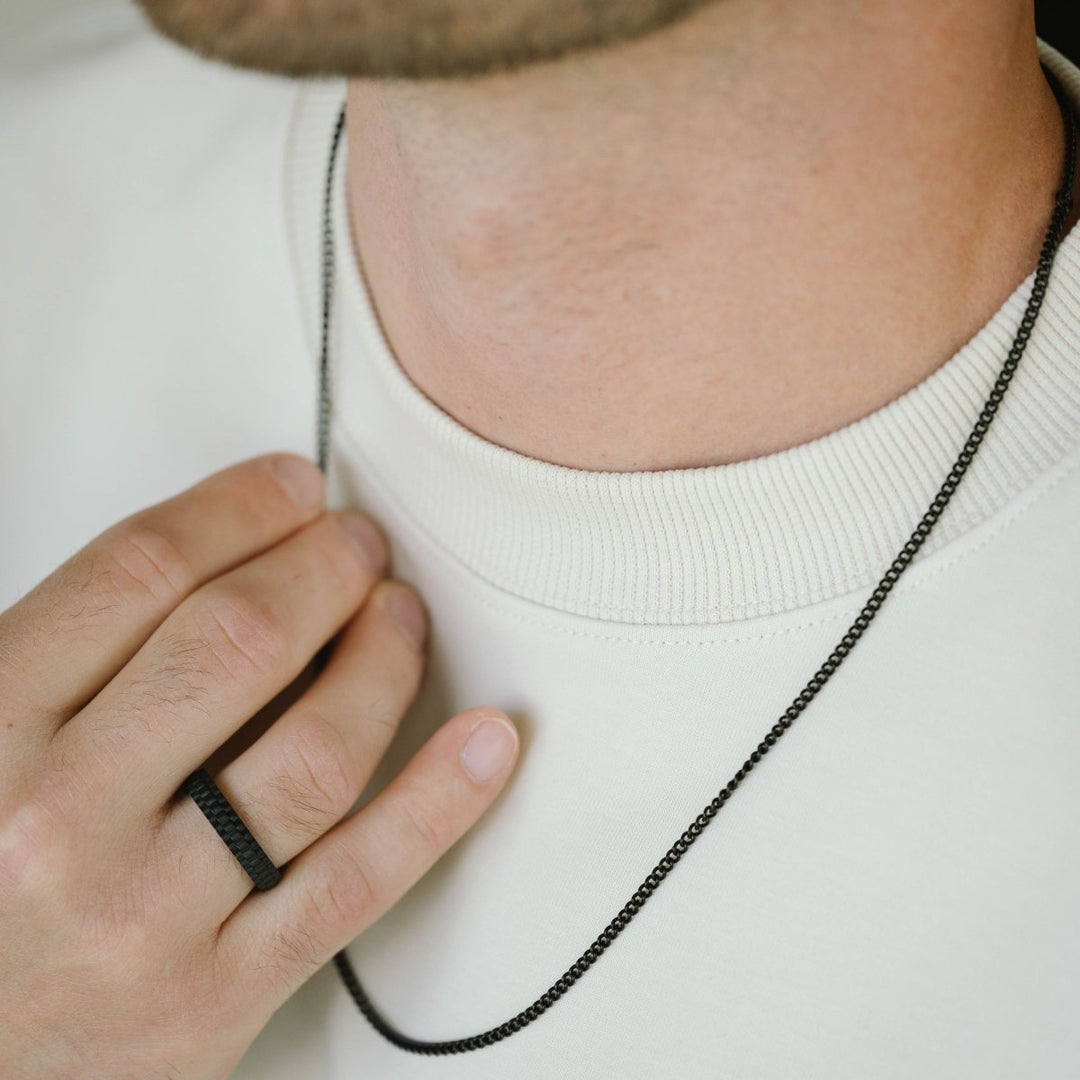 Niche Jewellery thin matte black stainless steel curb chain necklace worn by a man in a white sweater