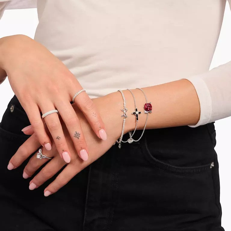Thomas Sabo sterling silver bracelet with bow motif and white zirconia stones, layered with other bracelets.
