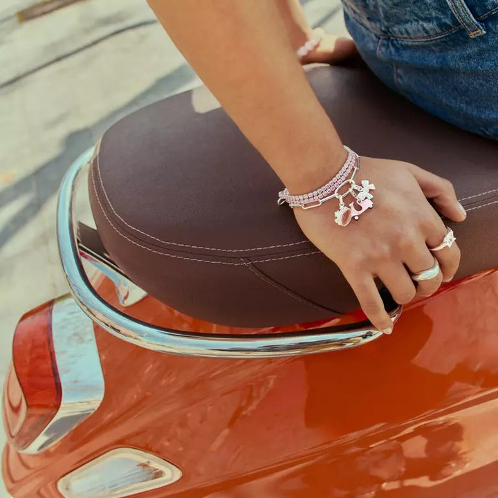 Niche Jewellery Thomas Sabo bow charm with cubic zirconia on a pink bracelet, worn by a woman on a scooter.