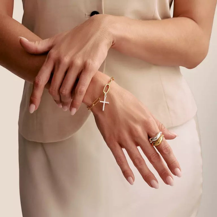 Niche Jewellery Thomas Sabo sterling silver cross charm pendant with white zirconia stones on a gold chain bracelet.