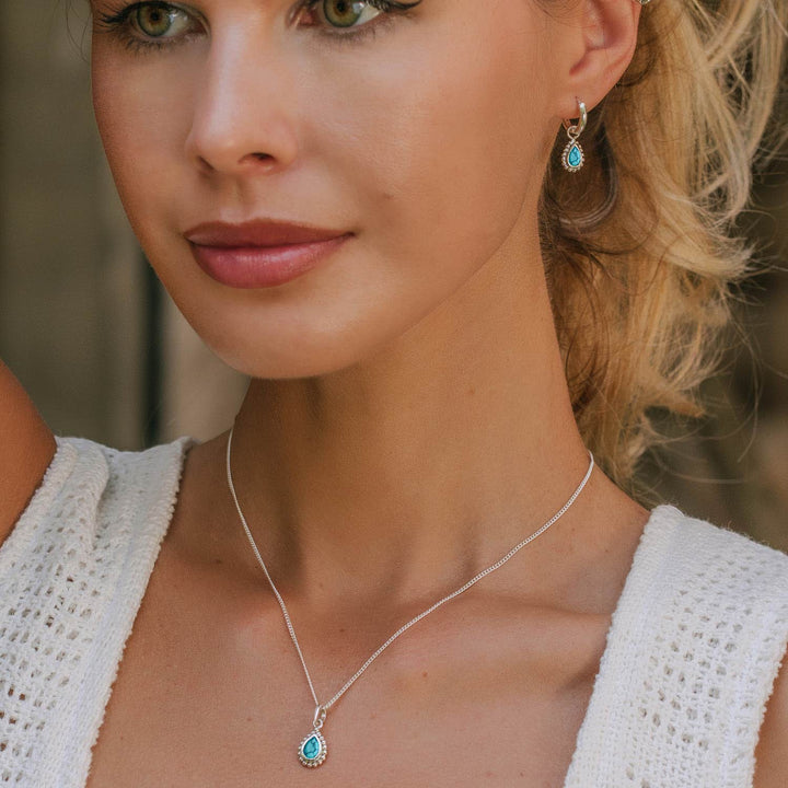 Niche Jewellery Charlotte's Web silver huggie hoops featuring pear-cut turquoise stones worn by a model