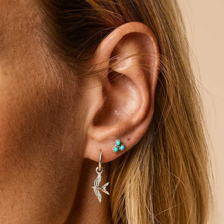 Niche Jewellery Charlotte's Web sterling silver stud earrings featuring three small turquoise stones on an earlobe