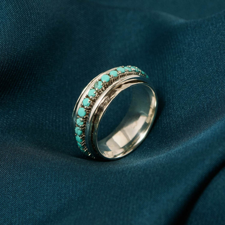 Niche Jewellery Charlotte's Web Parvati spinning ring in recycled sterling silver with turquoise stones on teal silk.