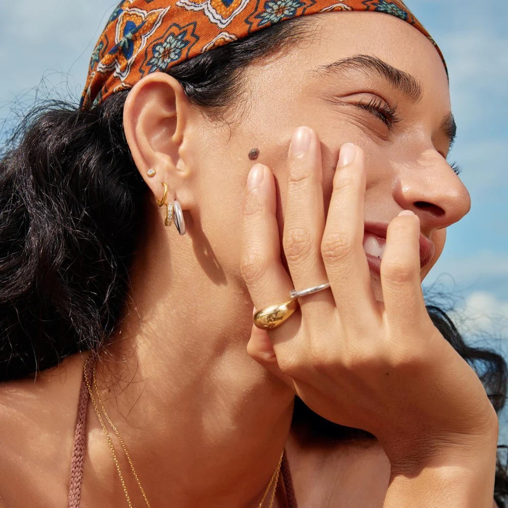 Niche Jewellery Ania Haie two-tone gold and silver hoop earrings with cubic zirconia worn by a smiling model.