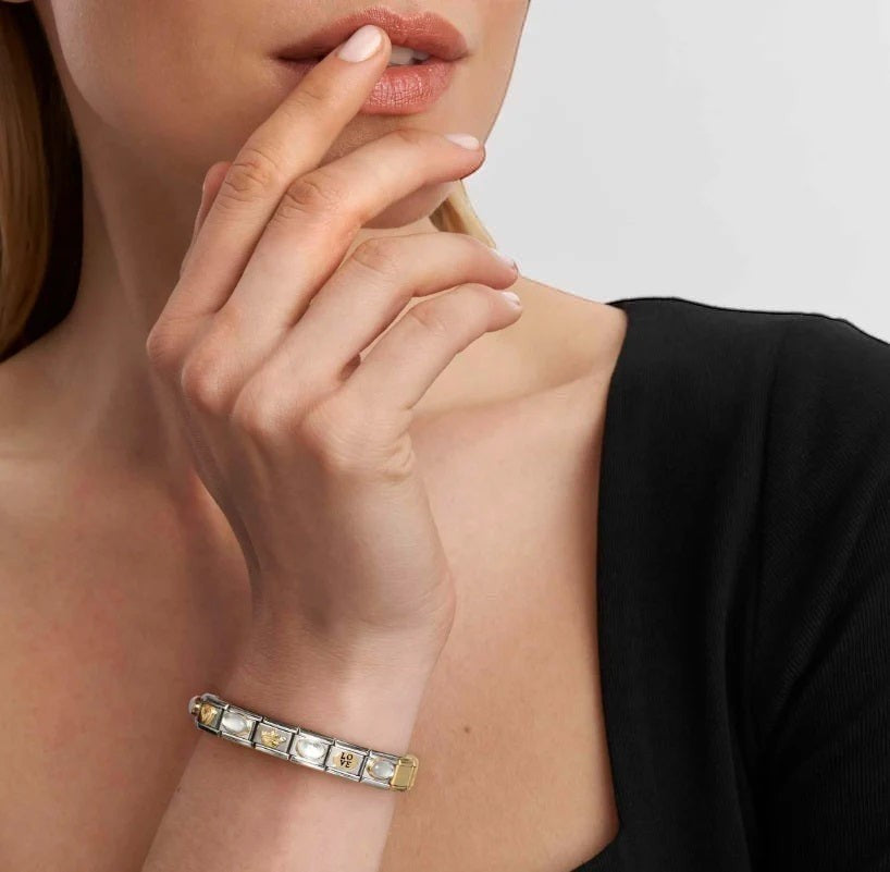 Niche Jewellery Nomination classic gold and light blue enamel forget-me-not charm bracelet on a woman's wrist.