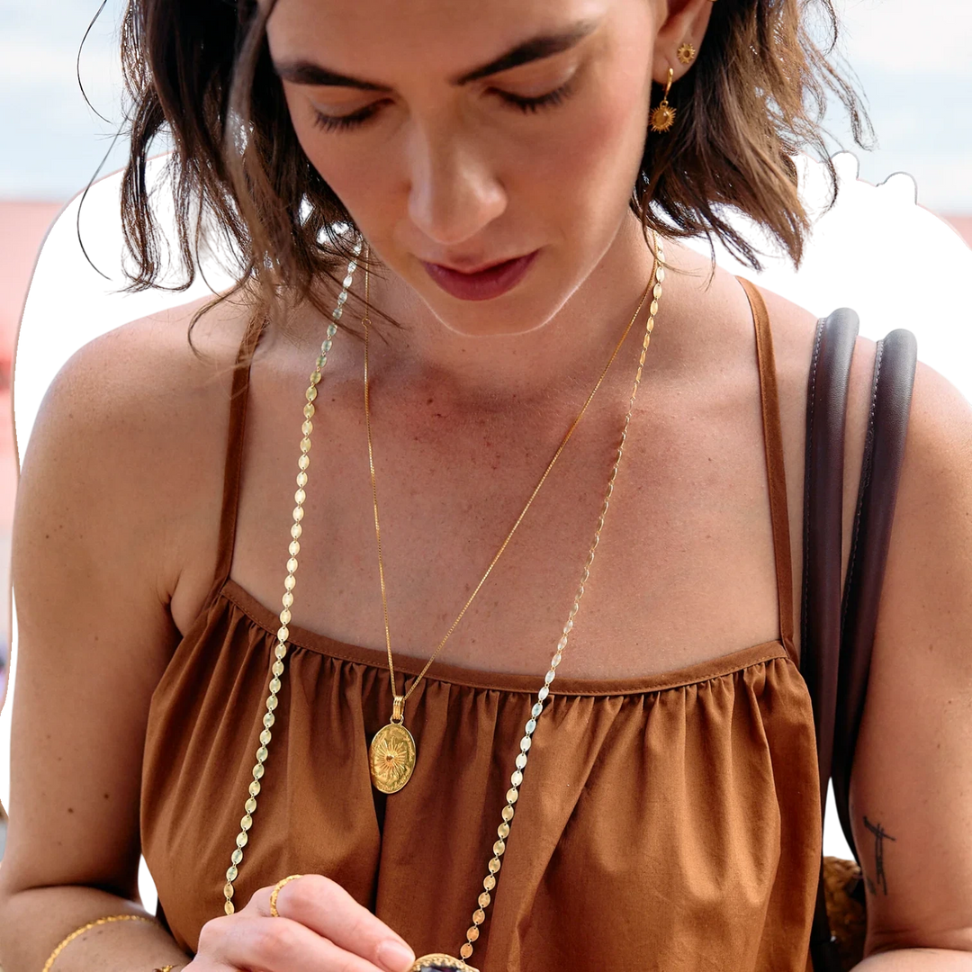 Rachel Jackson gold huggie hoop earrings with hand-carved citrine stones set in Art Deco rays. Model wears them with layered necklaces.