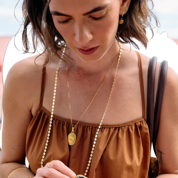 Rachel Jackson gold huggie hoop earrings with hand-carved citrine stones set in Art Deco rays. Model wears them with layered necklaces.